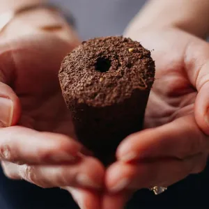 Händer som håller en planteringskapsel från Click & Grow för Smart Garden 9 Pro-systemet för inomhusodling