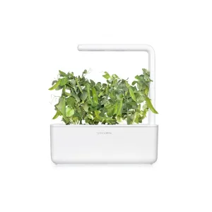 Click & Grow Smart Garden con plantas de guisante enano creciendo en una maceta de interior blanca