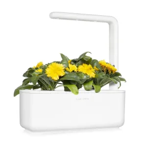 Jardín interior Click & Grow con flores de caléndula en flor y follaje verde en un sistema de luz de cultivo blanco