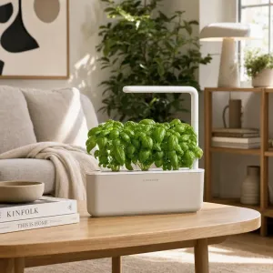 Jardin d’intérieur Smart Garden 3 de Click & Grow avec des plants de basilic feuillus et une lampe LED sur une table.